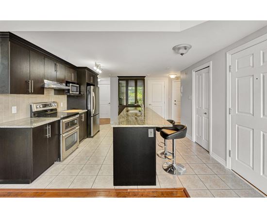 A kitchen with dark brown cabinets and a black island.