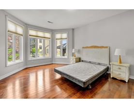A bedroom with a large bed, wooden floors, and a window with blinds.