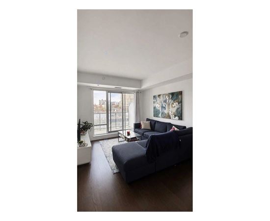 A living room with a grey couch and a painting on the wall.
