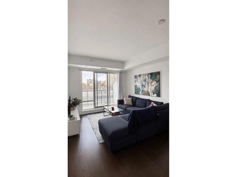 A living room with a grey couch and a painting on the wall.