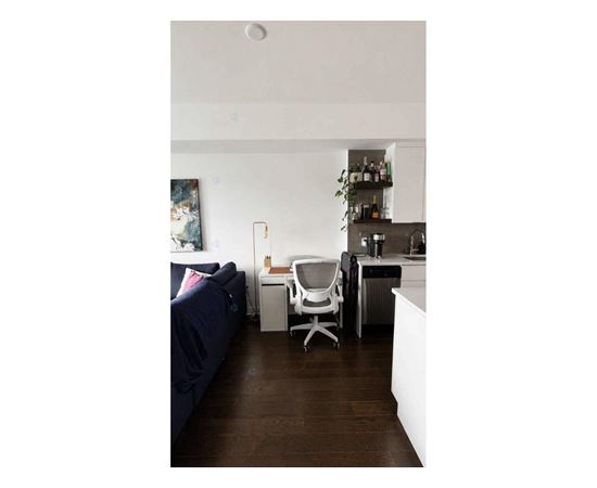 A living room with a couch, a chair, and a kitchen area.