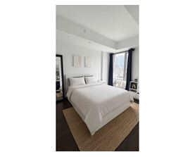 A bedroom with a large bed and a window with curtains.