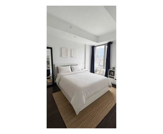 A bedroom with a large bed and a window with curtains.