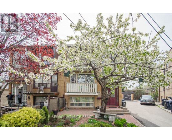 A tree with white blossoms is in front of a building with a balcony.