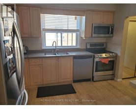 A kitchen with wooden cabinets and a stainless steel refrigerator.