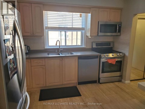 A kitchen with wooden cabinets and a stainless steel refrigerator.