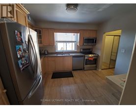 A kitchen with a refrigerator on the left and a microwave on the counter.