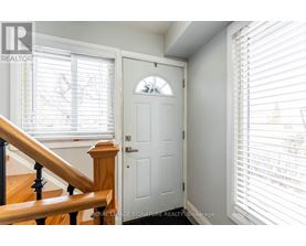 A white door with a window above it and a staircase to the left.