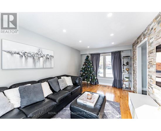 A living room with a black leather couch and a painting on the wall.
