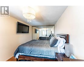 A bedroom with a bed, a television, and a chandelier.