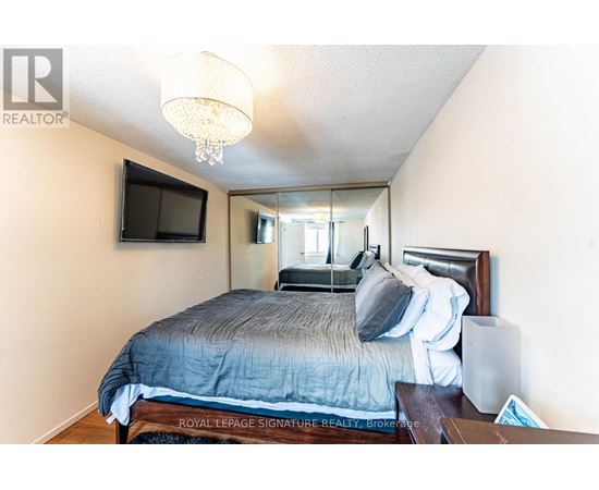 A bedroom with a bed, a television, and a chandelier.