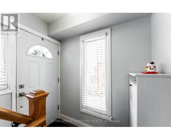 A white room with a door, a window with blinds, and a small table with a figurine on it.