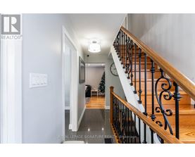 A hallway with a staircase and a Christmas tree in the background.