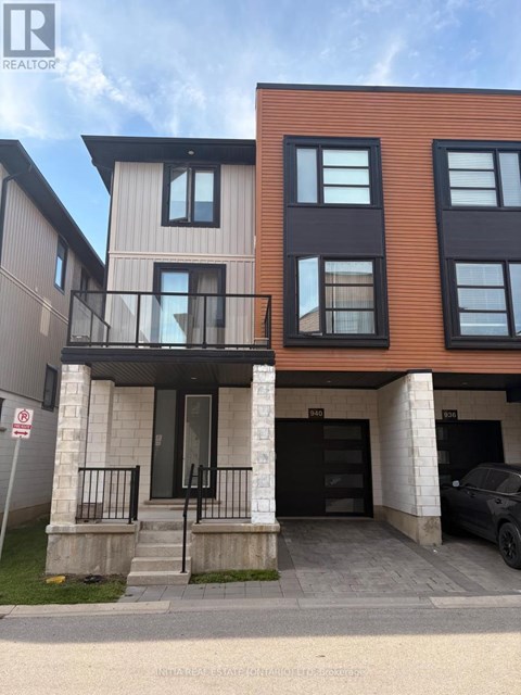 A modern two-story building with a balcony and a car parked in the driveway.