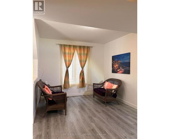 A living room with two chairs and a painting on the wall.