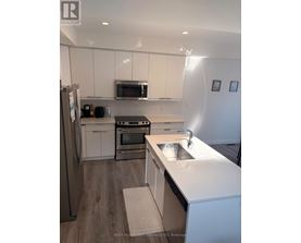 A kitchen with white cabinets and a stainless steel refrigerator.