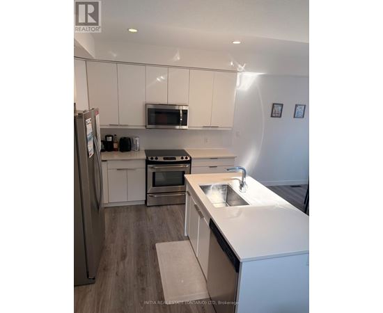A kitchen with white cabinets and a stainless steel refrigerator.