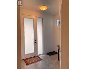A hallway with a rug on the floor and a door on the left.