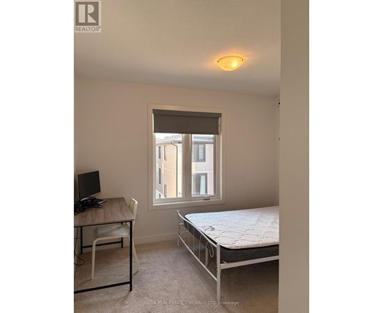 A bedroom with a bed, desk, and window.