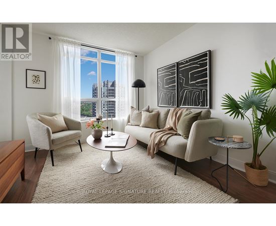A living room with a large window, a sofa, a chair, a coffee table, and a potted plant.