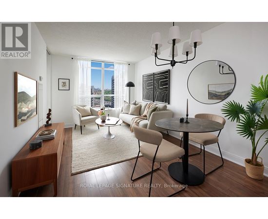 A living room with a round table and chairs, a rug, and a large window with a view of the city.