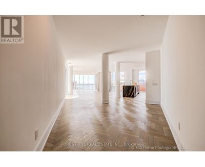 A spacious room with wooden flooring and a large window.