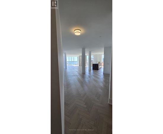 A spacious room with wooden flooring and a large window.