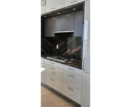 A modern kitchen with white cabinets and a dark countertop.