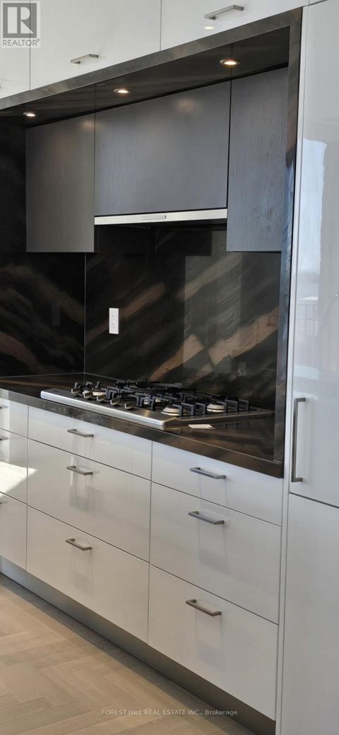 A modern kitchen with white cabinets and a dark countertop.