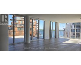 A large empty room with a view of the water and buildings outside.