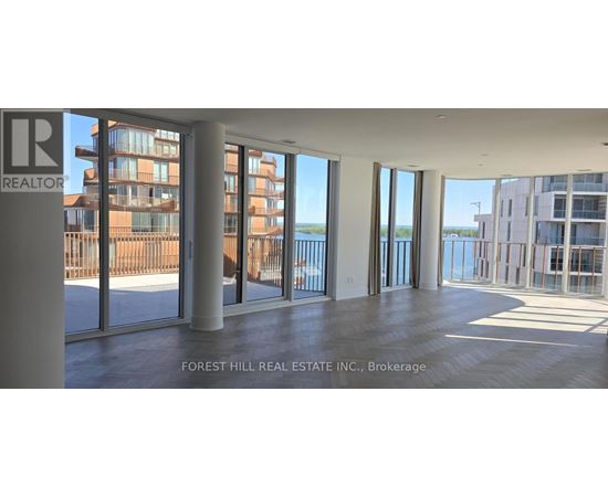 A large empty room with a view of the water and buildings outside.
