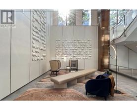 A modern living room with a large sculpture on the wall and a staircase in the background.