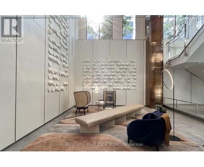 A modern living room with a large sculpture on the wall and a staircase in the background.