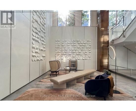 A modern living room with a large sculpture on the wall and a staircase in the background.