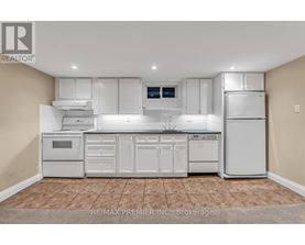 A white kitchen with a tile floor and white appliances.