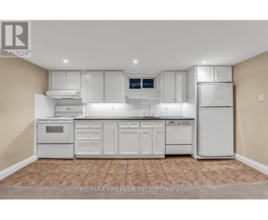 A white kitchen with a tile floor and white appliances.