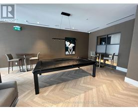 A room with a pool table and chairs.