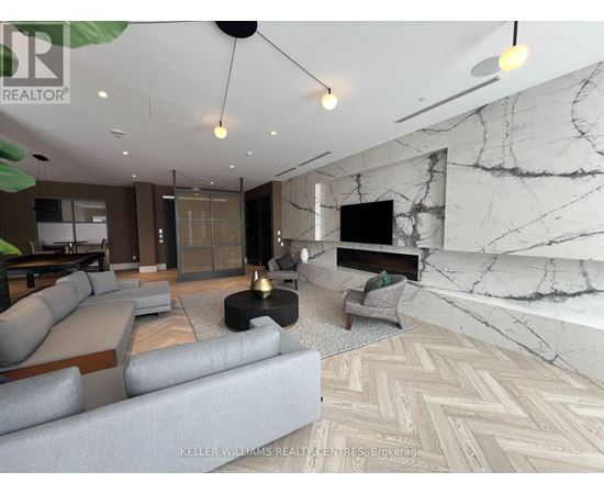 A living room with a grey sofa and a marble wall.