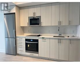 A modern kitchen with a stainless steel refrigerator and white cabinets.