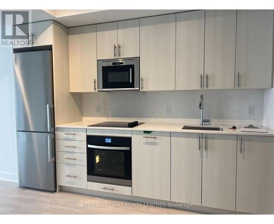 A modern kitchen with a stainless steel refrigerator and white cabinets.