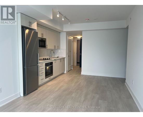 A spacious kitchen with a refrigerator, microwave, oven, and sink.