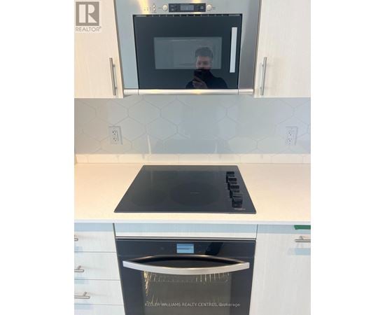A kitchen with a black microwave and a black stove top.