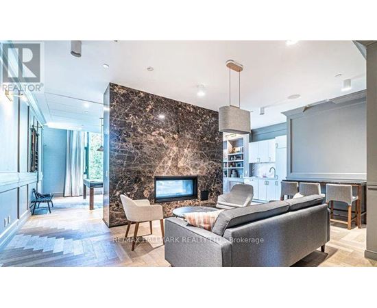 A living room with a grey couch and a stone wall.