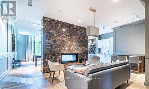A living room with a grey couch and a stone wall.