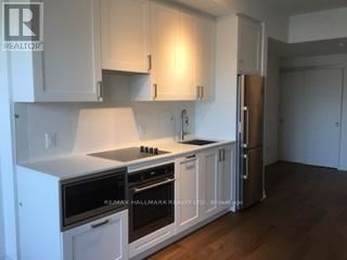 A kitchen with white cabinets and a stainless steel refrigerator.