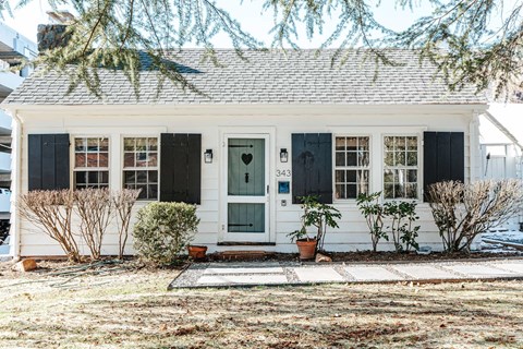 A small white house with a black front door and windows.
