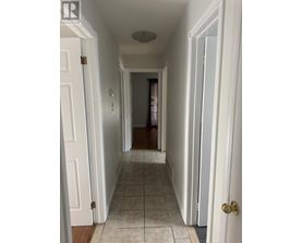 A hallway with white walls and a tiled floor.
