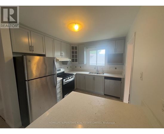 A kitchen with a refrigerator, sink, and cabinets.