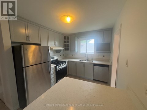 A kitchen with a refrigerator, sink, and cabinets.