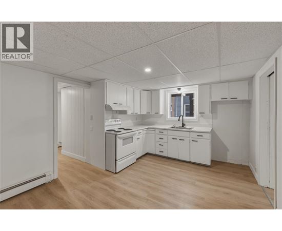 A white kitchen with wooden floors and white cabinets.